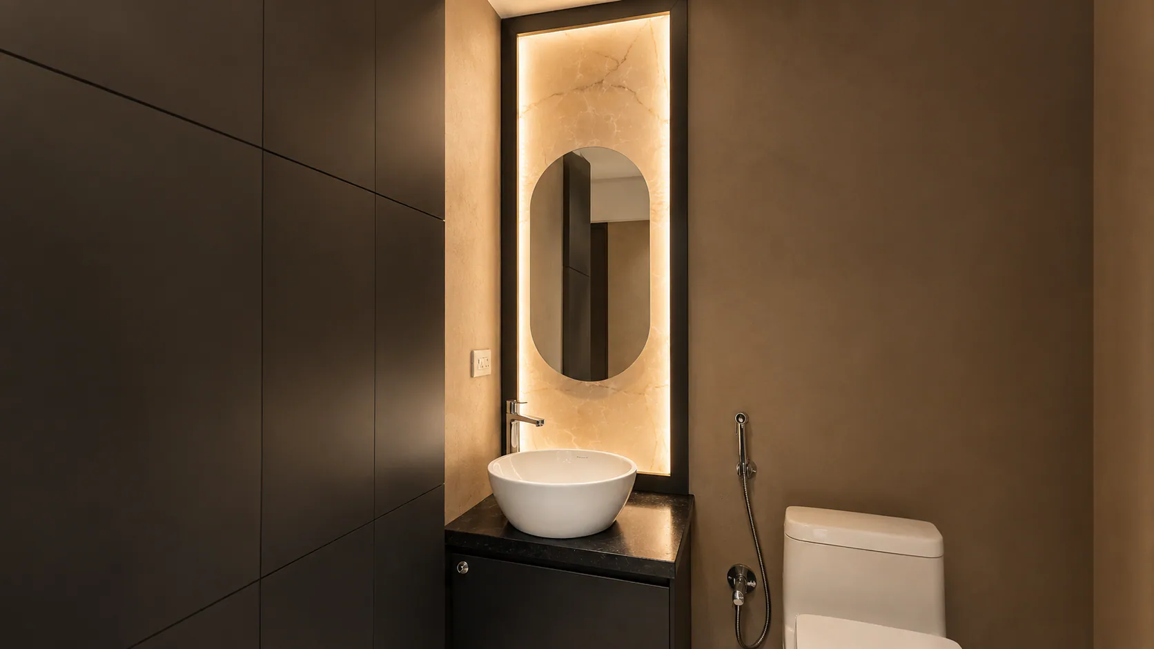Compact washroom with a basin, illuminated mirror and toilet.