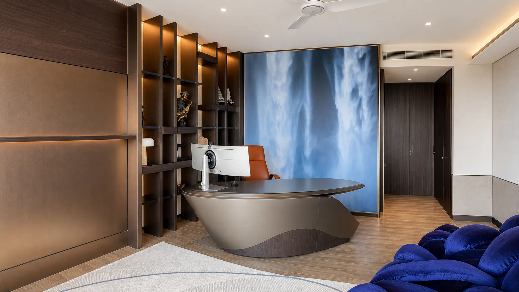 Home office with curved desk, shelving and a blue feature wall.
