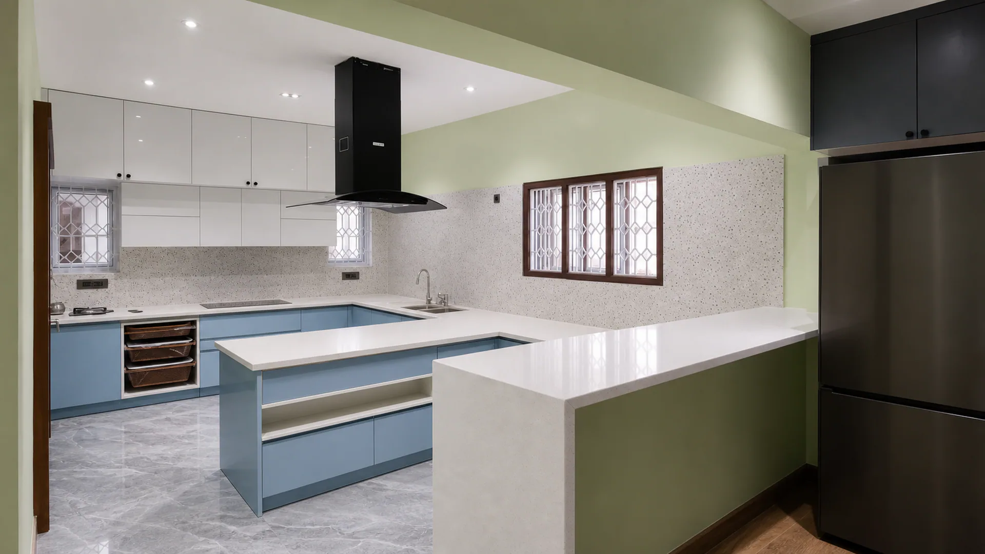 Wide kitchen view with blue cabinetry, white worktops, peninsula and dark refrigerator.