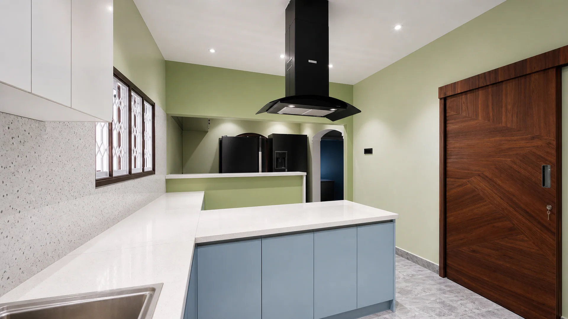 Kitchen entrance view with blue cabinetry, white island and dark hood.