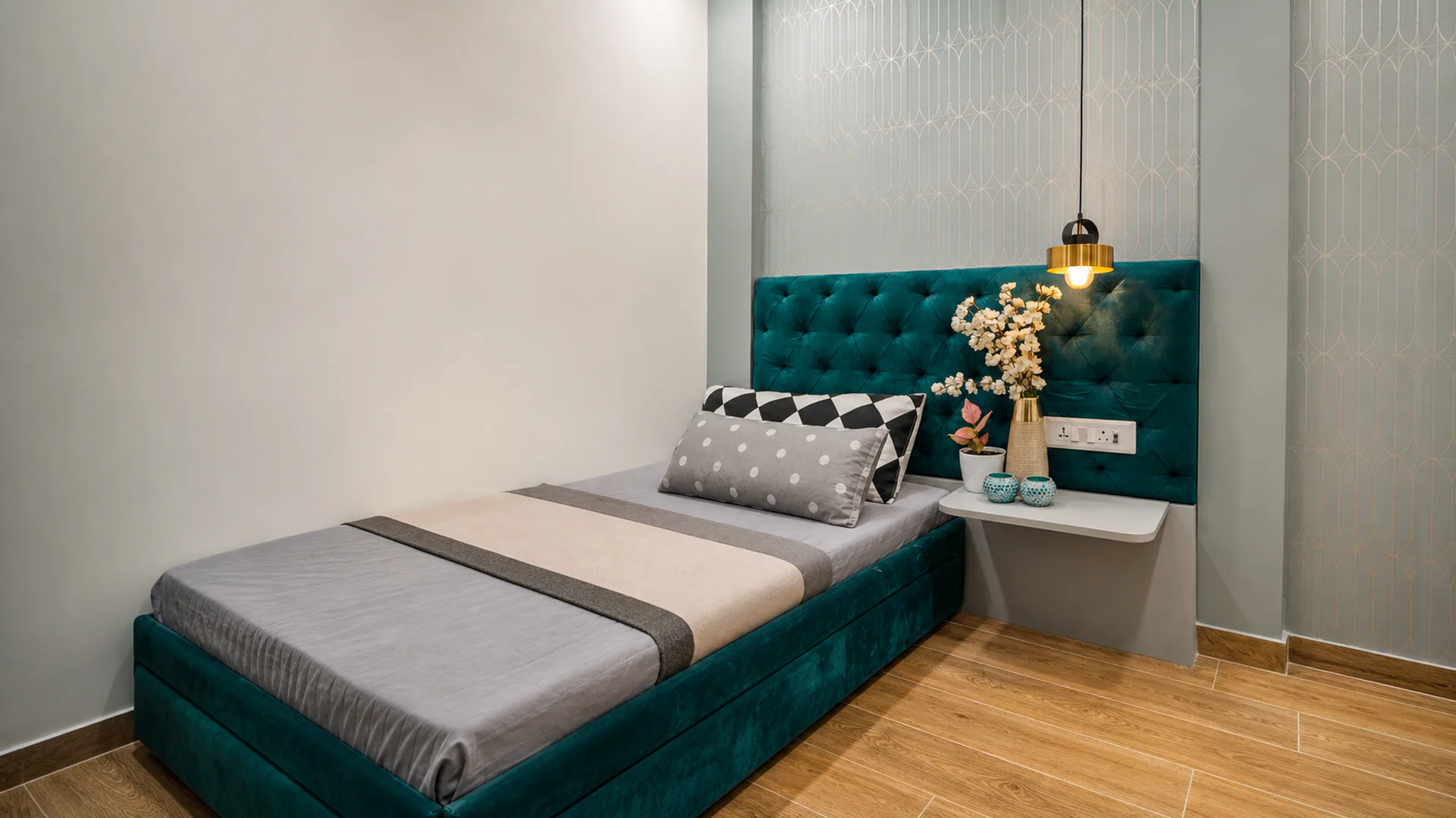 Bed with a teal upholstered frame beneath a pendant light.